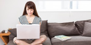 Woman sitting on sofa using laptop